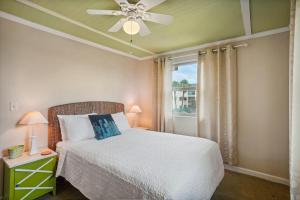 1 dormitorio con 1 cama, ventilador de techo y ventana en Friendly Native 507 en St Pete Beach