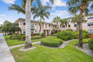 un grand immeuble avec des palmiers et de la pelouse dans l'établissement Friendly Native 507, à St. Pete Beach