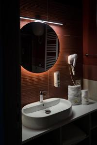 uma casa de banho com um lavatório e um espelho redondo em Rosy's Rooms em Patrica