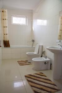 a white bathroom with a toilet and a sink at Raduga West Pineforest - коттедж в аренду на Иссык-Куле in Koshkolʼ