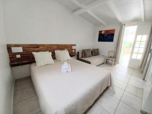 a bedroom with a large white bed and a couch at La Rose du Bresil Marie-Galante in Capesterre +37 photos