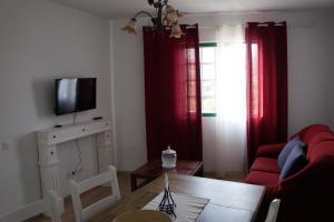 uma sala de estar com um sofá vermelho e uma televisão em Casa Teide em La Orotava