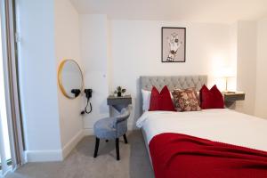 um quarto com uma cama com almofadas vermelhas e uma cadeira em LUXURY 2 Bedrooms - 2 BATHROOMS - F5 em Londres