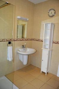 a bathroom with a sink and a clock on the wall at Twin Lake View - Bungalow in Pontoon in Foxford +18 photos