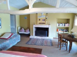 a living room with a fireplace and a table at Les Hôtes du Paradis in Forges