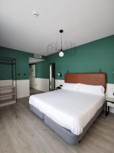 a bedroom with a large white bed and a green wall at Hotel Don Rodrigo in Palencia