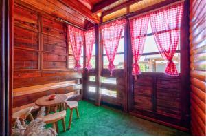 una habitación con cortinas rojas y una mesa en una cabaña en Zlatibor Brvnare Zakos en Zlatibor