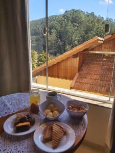 einen Tisch mit Teller mit Lebensmitteln auf einem Tisch mit einem Fenster in der Unterkunft Pousada Winterhaus in Monte Verde