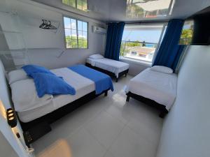 Habitación pequeña con 2 camas y ventana en Apartamentos Chalet del Mar en San Andrés