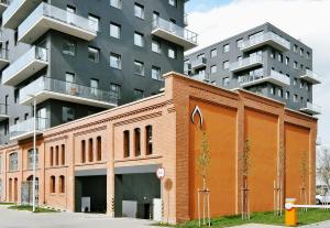 an orange brick building in front of a tall building at City Comfort Wrocław in Wrocław