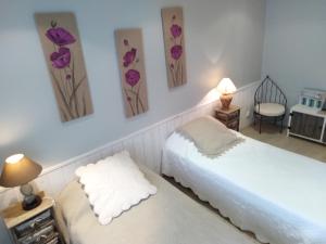 two beds in a room with purple flowers on the wall at Les Hôtes du Paradis in Forges +36 photos