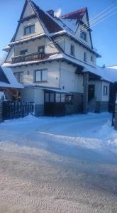 Une grande maison blanche avec de la neige au sol dans l'établissement Pokoje u Mariana, à Groń