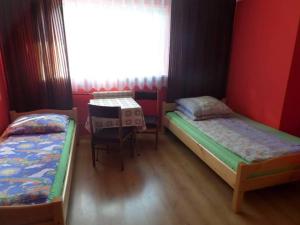 a room with two beds and a table and a window at Pokoje u Mariana in Groń
