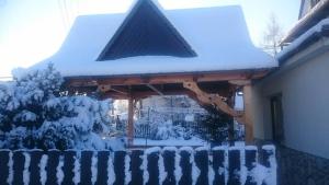 a gazebo covered in snow with a fence at Pokoje u Mariana in Groń