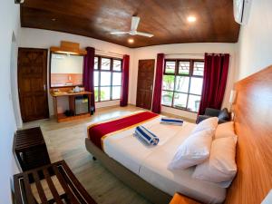 a bedroom with a large bed with red curtains at Lagoon View Maldives in Bodufolhudhoo