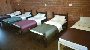 a group of beds lined up against a brick wall at Maravakandy Farm and Guest House in Masinagudi