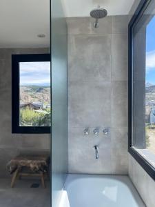 a bathroom with a bath tub with a window at Desierto Suites in El Chalten