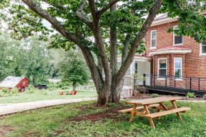 una mesa de picnic de madera junto a un árbol frente a una casa en Camp Trapezium, en Amherst