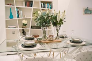 a dining room table with plates and vases of flowers at Valletta Dream Penthouse in Valletta