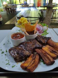 a white plate with steak and potatoes and other foods at Casona Tica Linda in Sarapiquí