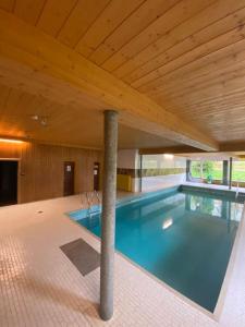 een zwembad in een gebouw met een houten plafond bij Exklusives Apartment mit Schwimmbad im Allgäu in Oy-Mittelberg