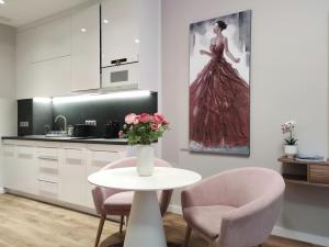 una cocina con mesa y 2 sillas y un jarrón de flores en Spa Residence Carbona Mona Lila Apartman en Hévíz