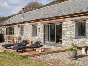 una casa de ladrillo con una terraza de madera delante de ella en The Pendre Longbarn en Pentre-briwnant