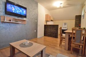 a living room with a table and a television on a wall at Apartman Sofija in Kaludjerske Bare