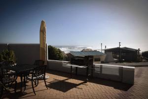 un patio con mesa, sillas y el océano en Apt on Beach front, Modern 2BR Solar, 50m to beach en Strandfontein
