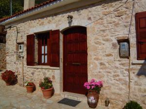 a stone house with a wooden door and some flowers at Sponsor of the E4 Peloponnese Trail in Daras