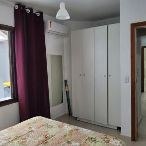 um quarto com uma cama, armários brancos e uma janela. em Condominio Frente do mar! Lindo apartamento! em Florianópolis