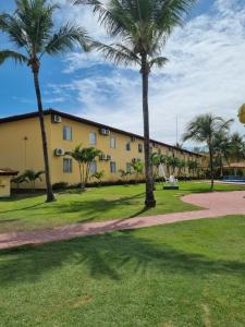 un bâtiment avec des palmiers dans un parc dans l'établissement LC TEMPORADAS PORTOBELLO PARK HOTEL, à Porto Seguro