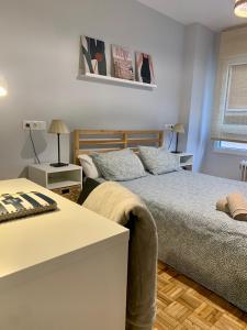 1 dormitorio con 2 camas y mesa. en Apartamento con garaje a un paso de la playa, en Gijón