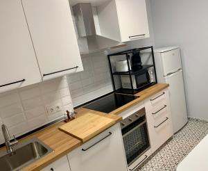 a kitchen with white cabinets and a sink and a microwave at Apartamento con garaje a un paso de la playa in Gijón
