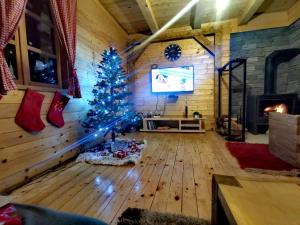 a christmas tree in a room with a fireplace at Wooden house with a waterfall "Stipanov mlin" in Plitvička Jezera