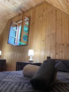 1 dormitorio con paredes de madera y 1 cama con ventana en Wooden house with a waterfall "Stipanov mlin" en Lagos de Plitvice