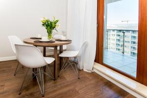 een eetkamer met een tafel en stoelen en een raam bij erApartments Oxygen Residence in Warschau