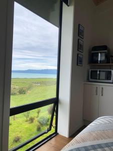 a bedroom with a large window with a view of a field at Toi Toi Papatotara in Papatotara