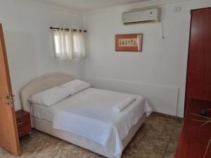 a bedroom with a bed with white sheets and a window at Loren Village in Neve Zohar