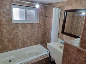 a bathroom with a tub and a sink and a mirror at Loren Village in Neve Zohar