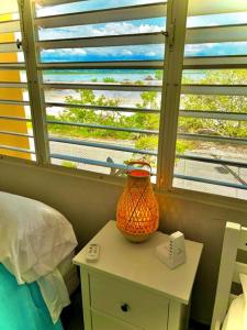 Schlafzimmer mit einem Bett, einem Tisch und einem Fenster in der Unterkunft 2-BR Modern Oceanfront Apt Steps from Playa Sucia in Cabo Rojo