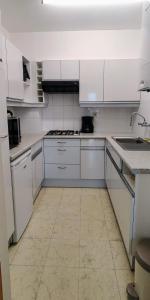 eine weiße Küche mit weißen Schränken und Fliesenboden in der Unterkunft Le Zandkreek Plage & Centre - 2 Ch in Koksijde + 6 Fotos