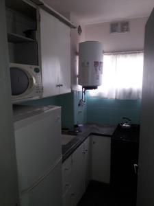 eine kleine Küche mit weißen Schränken und einer Mikrowelle in der Unterkunft Dpto Olavarria in Mar del Plata