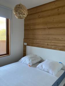een slaapkamer met een wit bed en een houten muur bij Mont Vallon Lodge- Méribel Mottaret, Skis aux pieds, proche du centre et tout confort, Parking gratuit et Linge fourni in Méribel