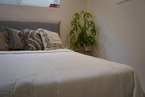 - un lit blanc avec des oreillers et une plante dans la chambre dans l'établissement סיני 48 מלון דירות בוטיק, à Vered Yeriho