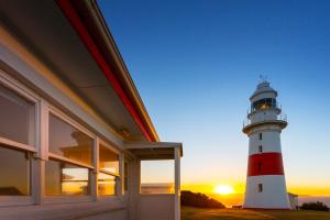 un faro sentado al lado de una casa con la puesta de sol en Low Head Pilot Station en Low Head