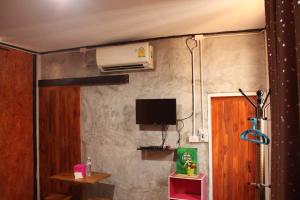 Cette chambre est dotée d'un mur avec une télévision et une porte. dans l'établissement เฮือนอุ้ยดี1, à Ban Khua Nam Chun