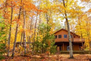 a wooden house in the woods with trees at Fall Getaway Resort-3 KING suites, Dog-Friendly in Seeley