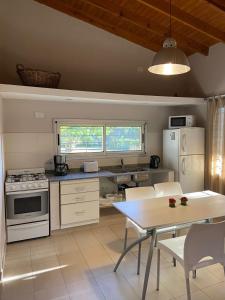 una cocina con electrodomésticos blancos y una mesa con sillas. en Casa/Quinta Las Hayas (A 5 CUADRAS DE LA LAGUNA) en Chascomús