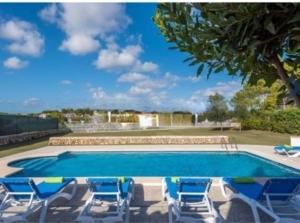 una piscina con sedie blu e un albero di Villa etxe txekia a Cala Galdana